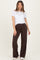 woman wearing a white short sleeve top and brown maternity wide-leg pants, posing with a relaxed smile