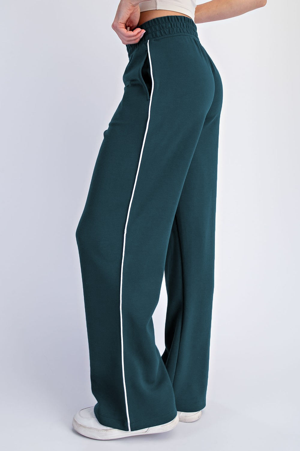 woman wearing dark green wide-leg sweatpants with white side stripes and an elastic waistband