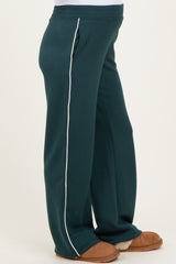 woman wearing teal maternity lounge pants with white side stripes and cozy slippers
