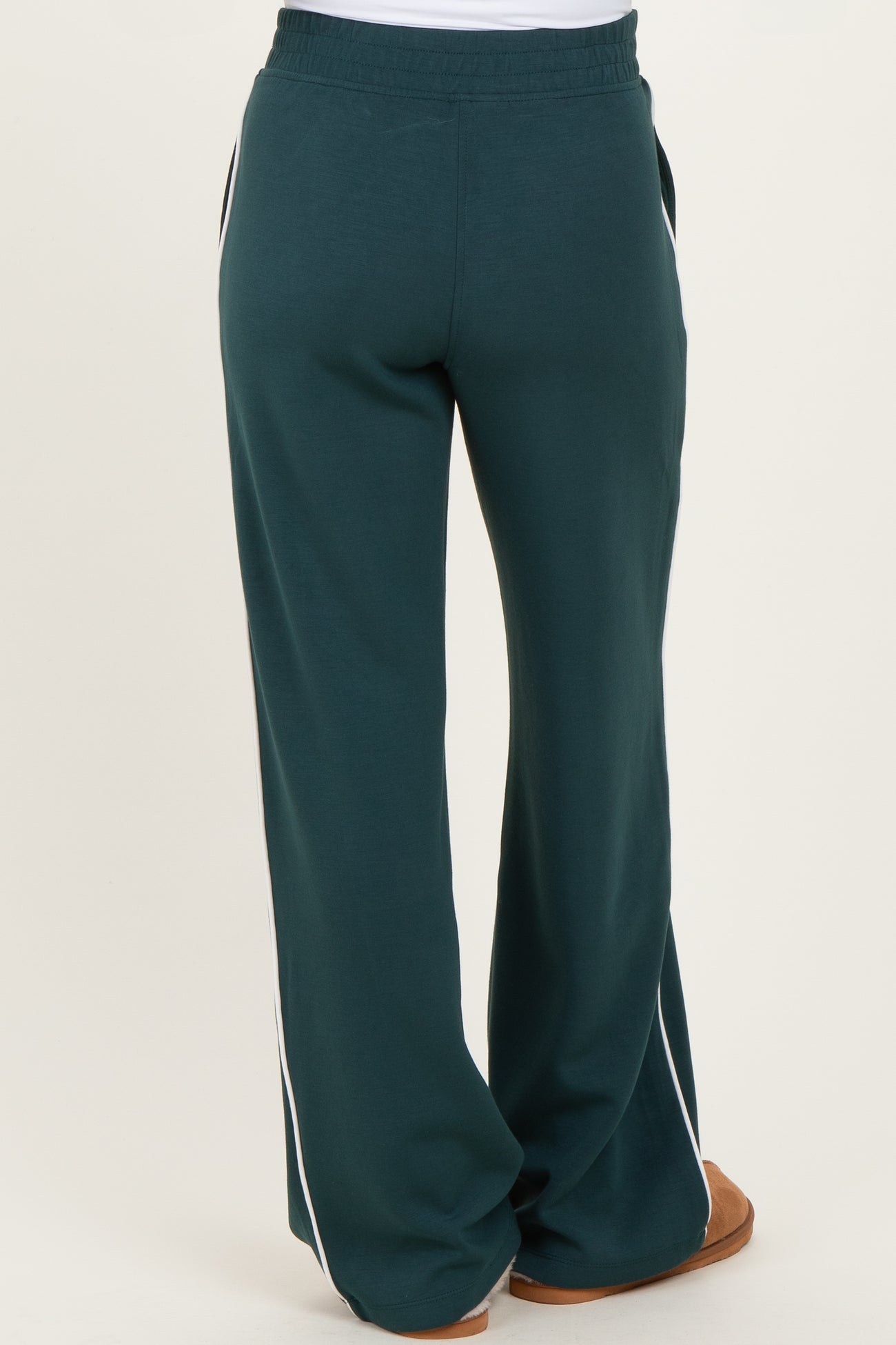 woman wearing green maternity sweatpants with side stripes, showing the back view