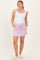 woman wearing a white maternity tank top and a pink drawstring maternity skirt with pockets, showing her baby bump