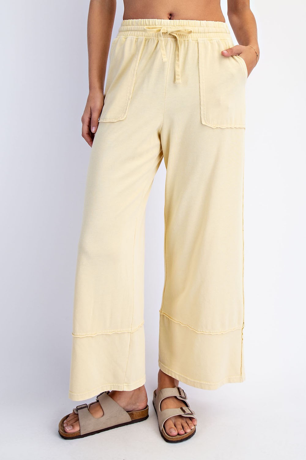 woman wearing light yellow wide-leg pants with two front pockets and an elastic waistband
