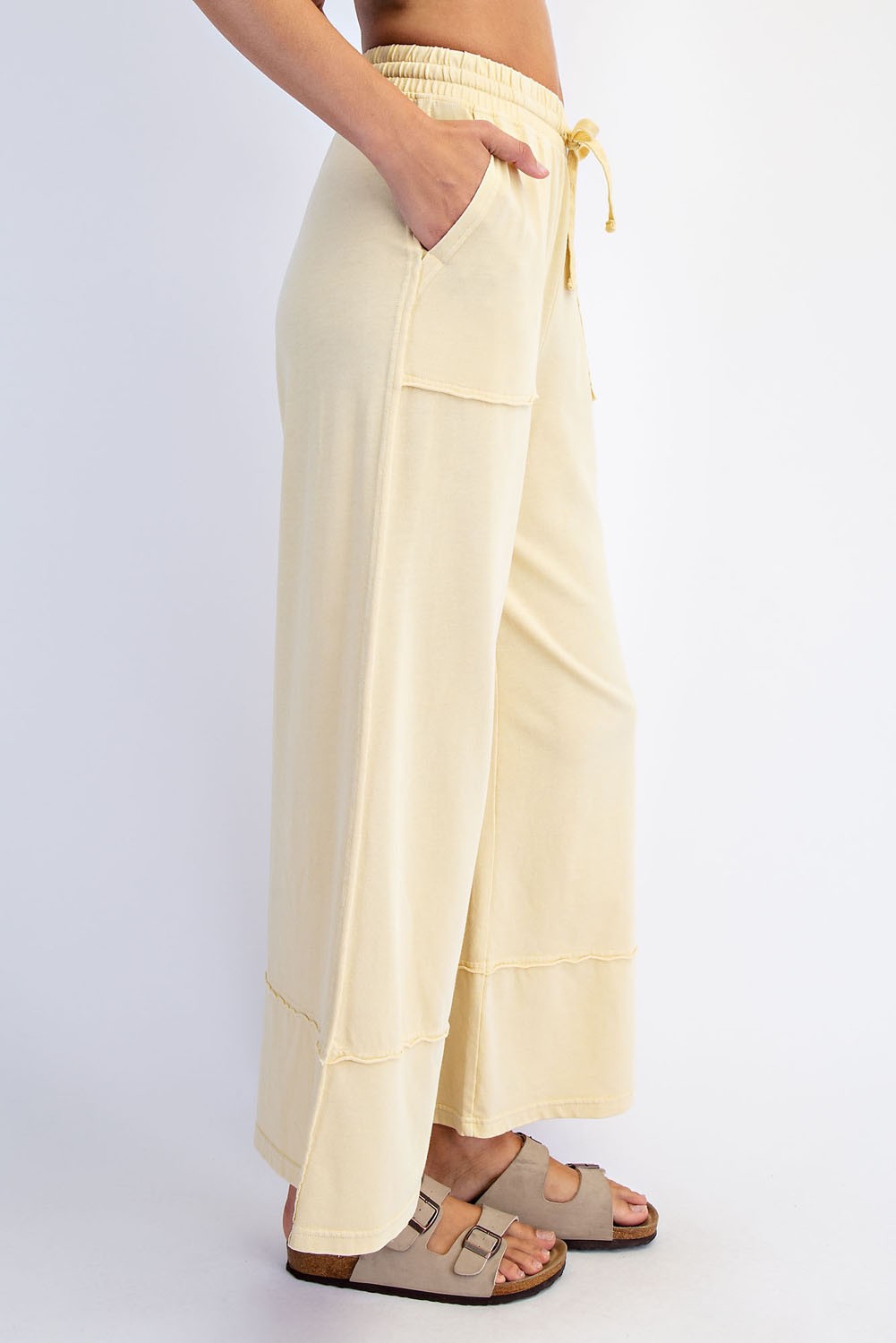 woman wearing light yellow wide-leg lounge pants with pockets and a drawstring waist