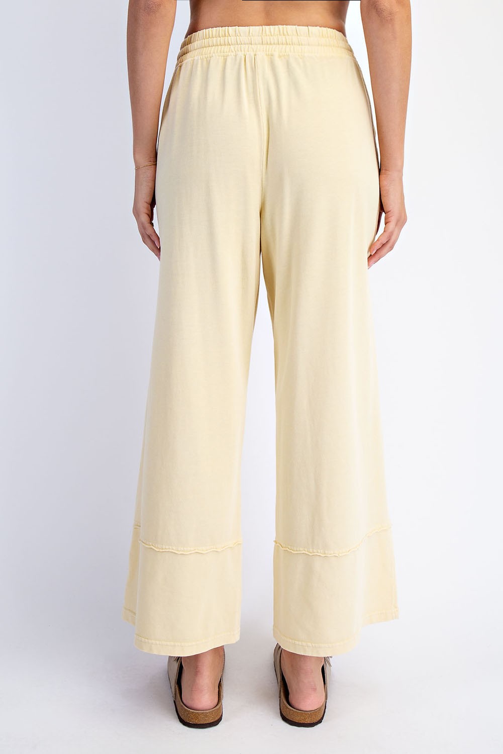 woman wearing yellow wide-leg pants with a relaxed fit and a tiered hemline, shown from the back