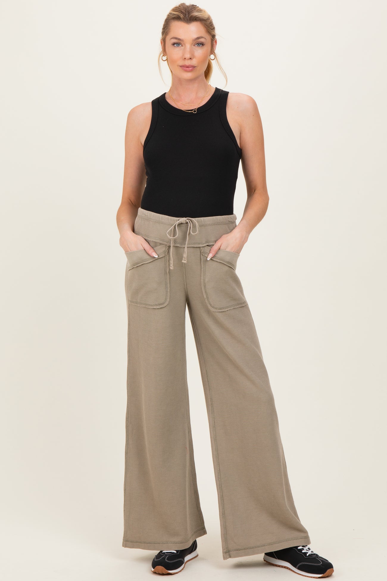 woman wearing a black sleeveless maternity top and beige wide leg pants with pockets