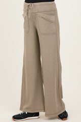 woman wearing beige wide-leg maternity lounge pants with pockets and an elastic waistband