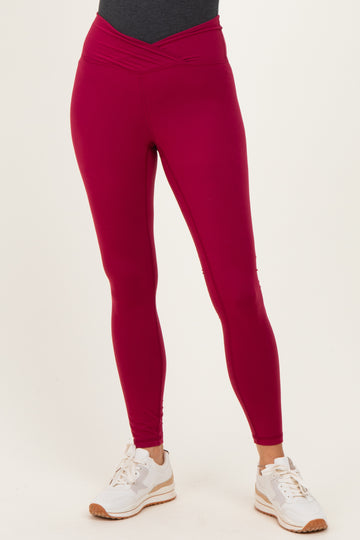 woman wearing fuchsia high-waisted active leggings with a crossover waistband and white sneakers
