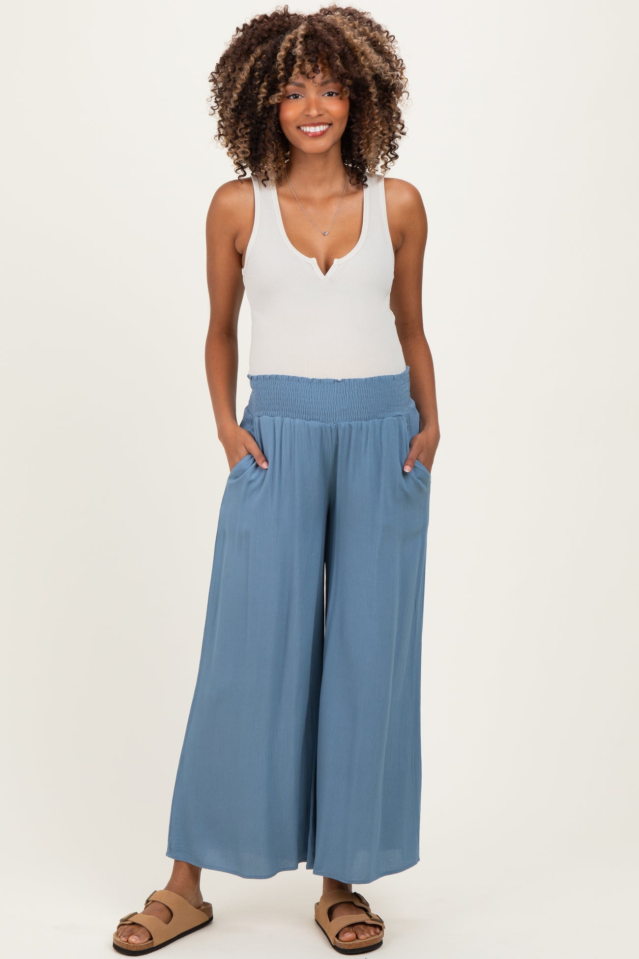 woman wearing a white tank top and light blue maternity wide-leg pants with pockets