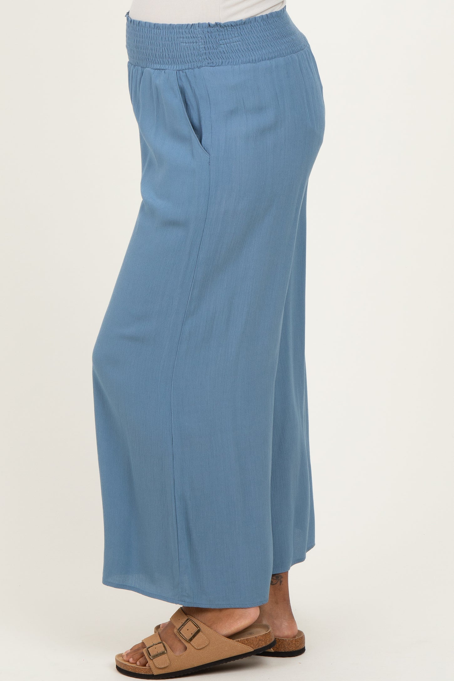 woman wearing light blue maternity wide-leg pants with a smocked waistband and side pockets