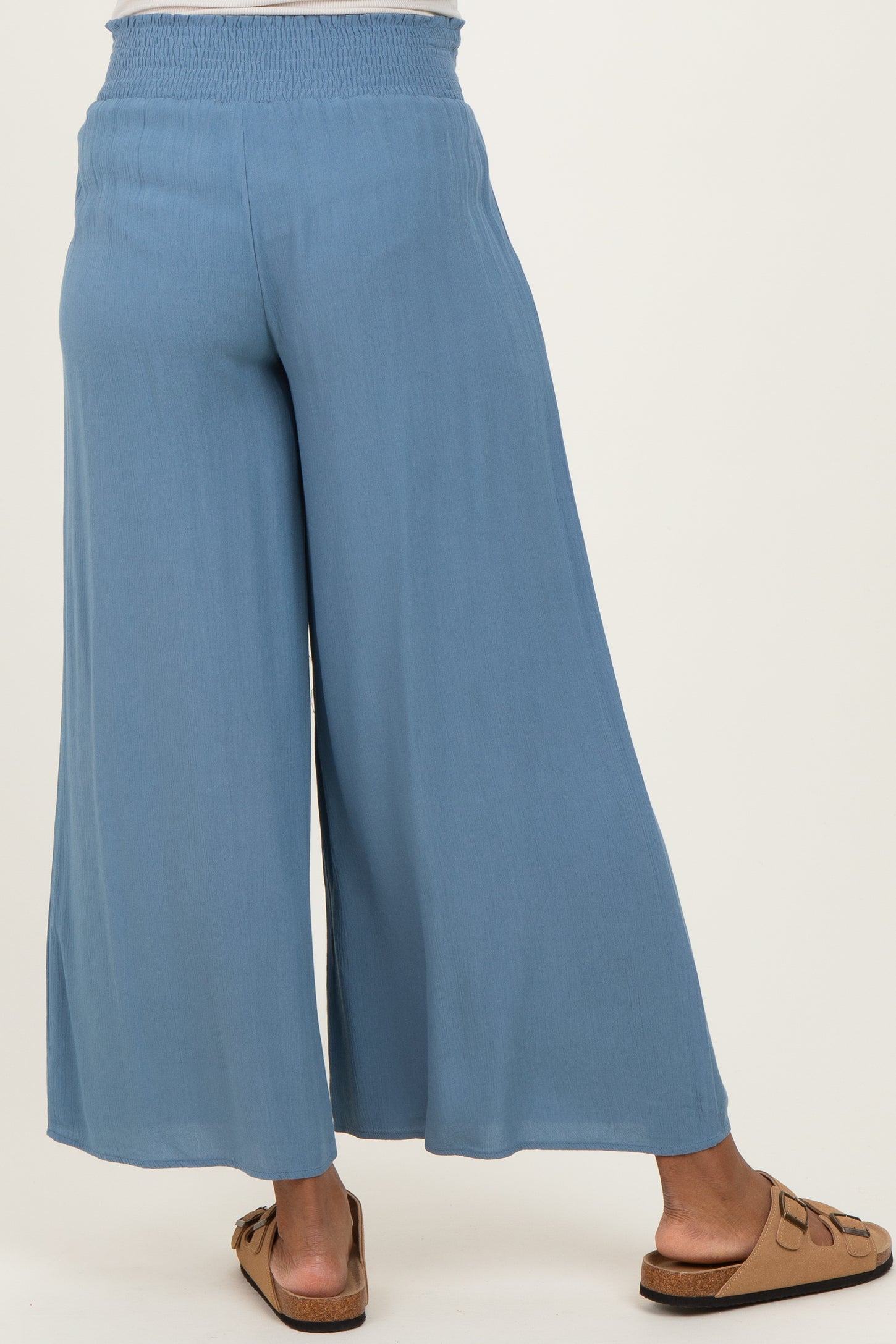 woman wearing light blue maternity wide-leg pants with a smocked waistband from the back