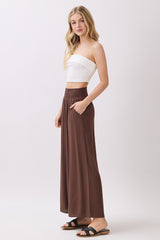 woman wearing a white strapless crop top and brown wide-leg pants with pockets
