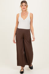 woman wearing a white sleeveless maternity top and brown wide-leg maternity pants