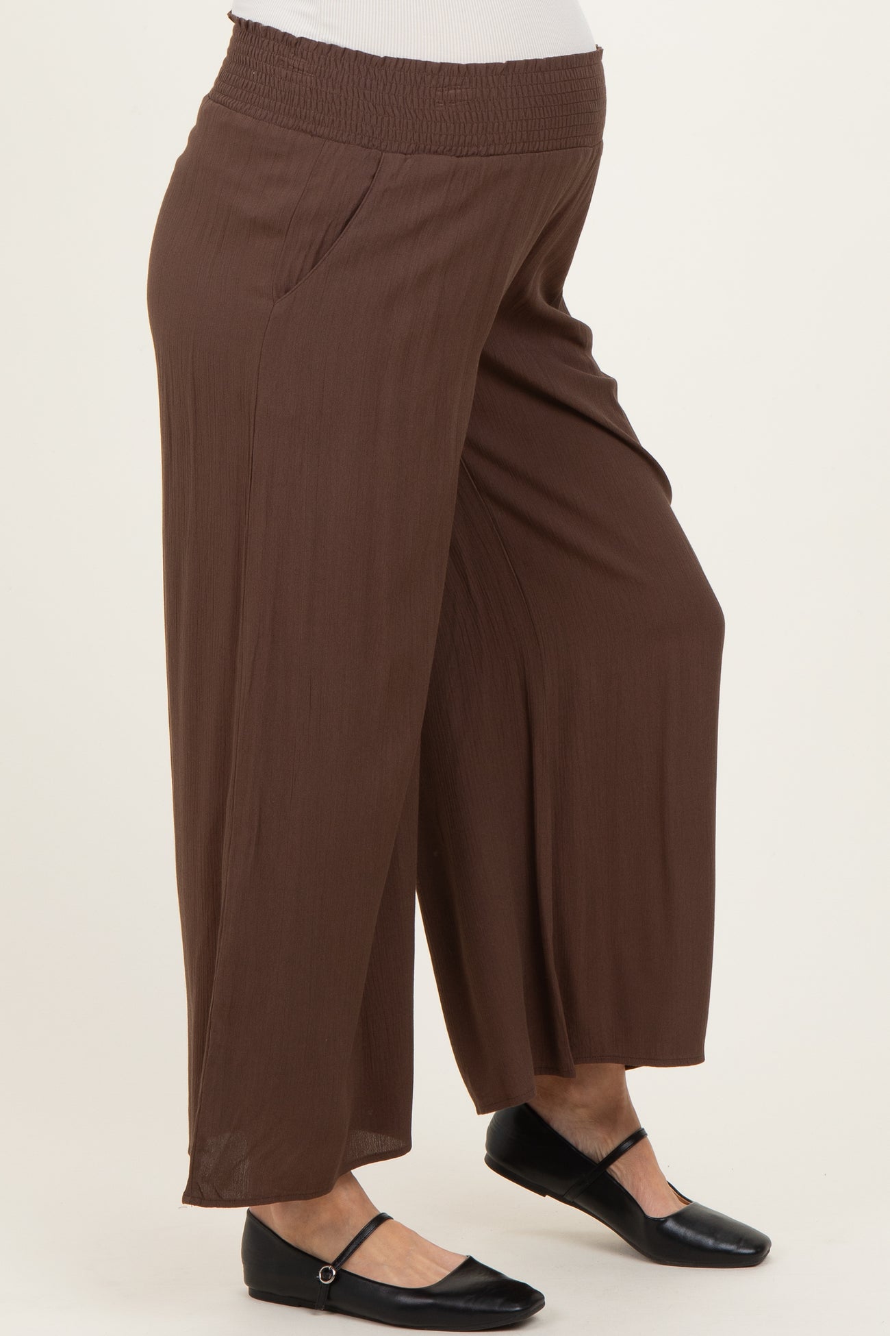 woman wearing brown maternity wide-leg pants with a smocked waistband and side pockets