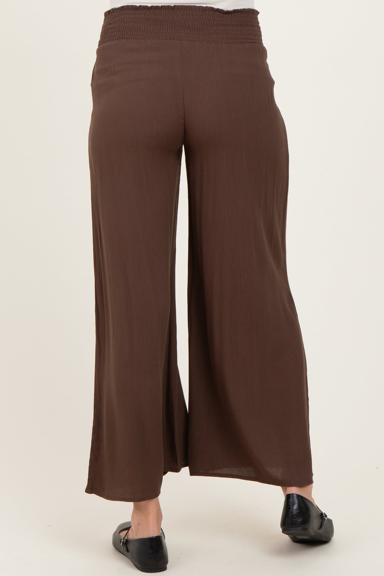 woman wearing brown maternity palazzo pants, showing the back view with a smocked waistband