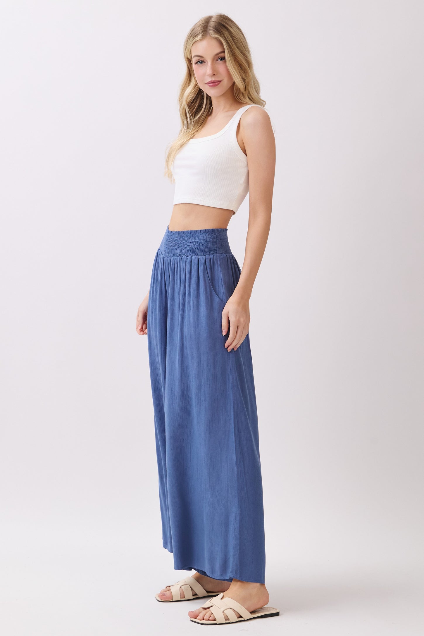 woman wearing a white crop top and flowy blue maxi skirt with a smocked waistband
