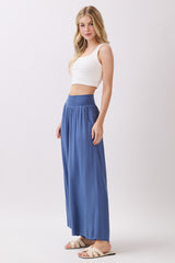 woman wearing a white crop top and flowy blue maxi skirt with a smocked waistband