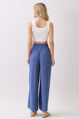 woman wearing a white crop top and blue wide-leg pants, seen from the back