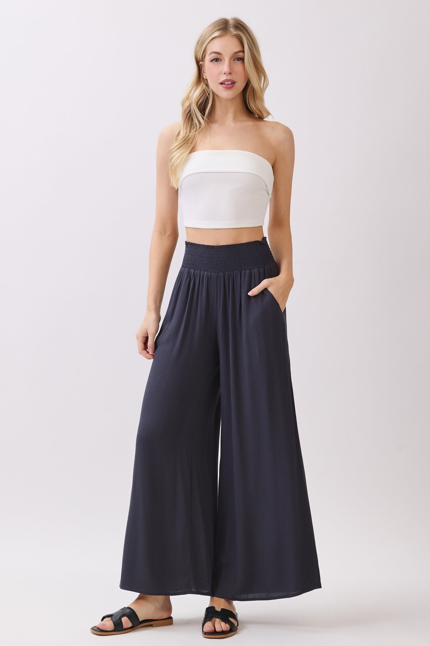 woman wearing a white strapless top and navy wide-leg pants with pockets