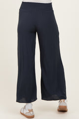 maternity wear navy blue wide leg pants with a smocked waistband, shown from the back, model wearing sandals