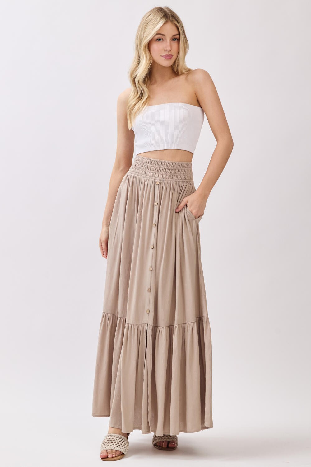 woman wearing a white strapless top and a beige maxi skirt with buttons and a smocked waist