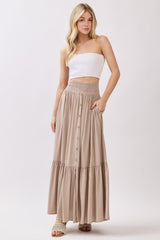 woman wearing a white strapless top and a beige maxi skirt with buttons and a smocked waist