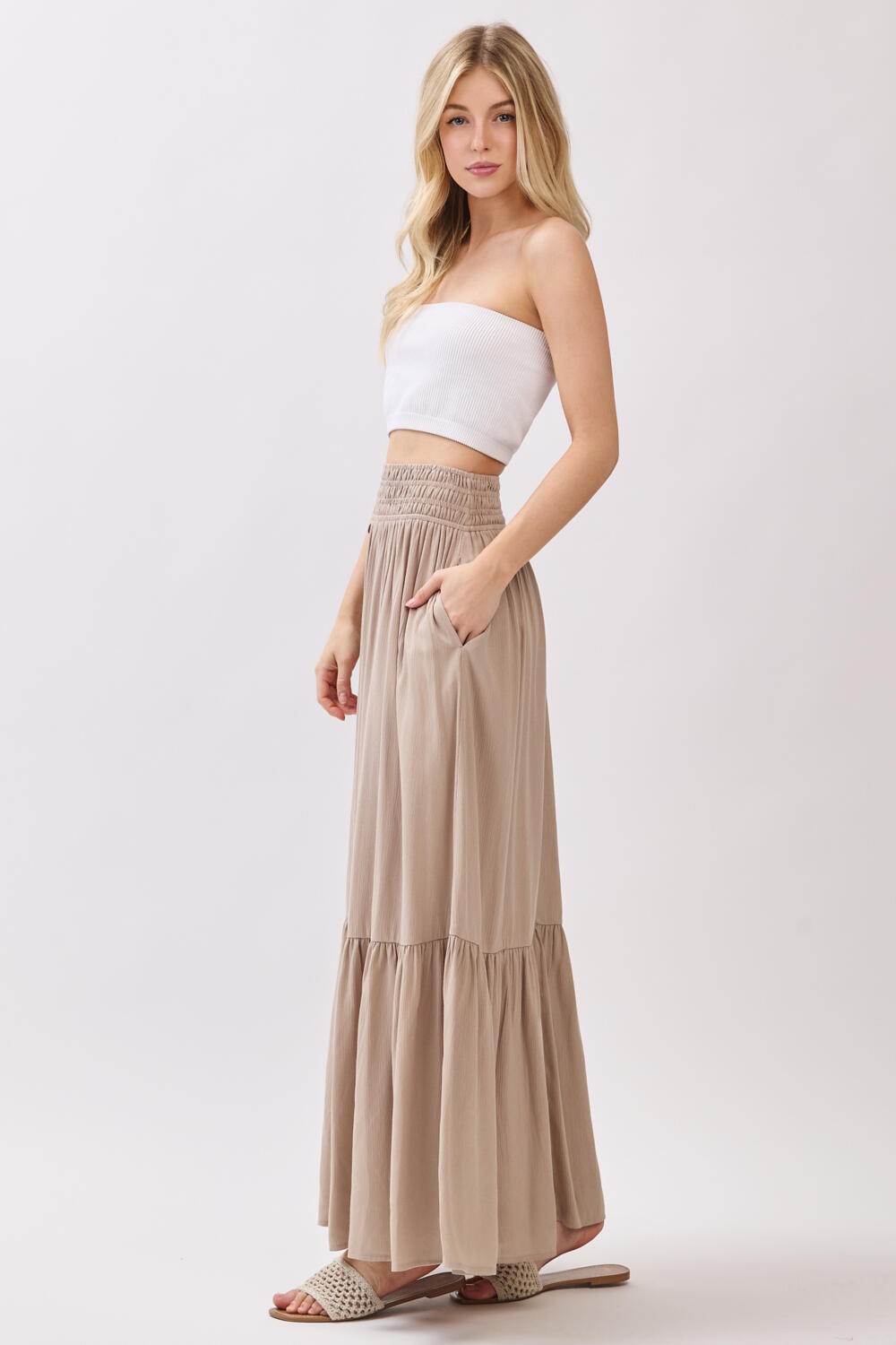 woman wearing a white strapless top and a long beige tiered maxi skirt with pockets