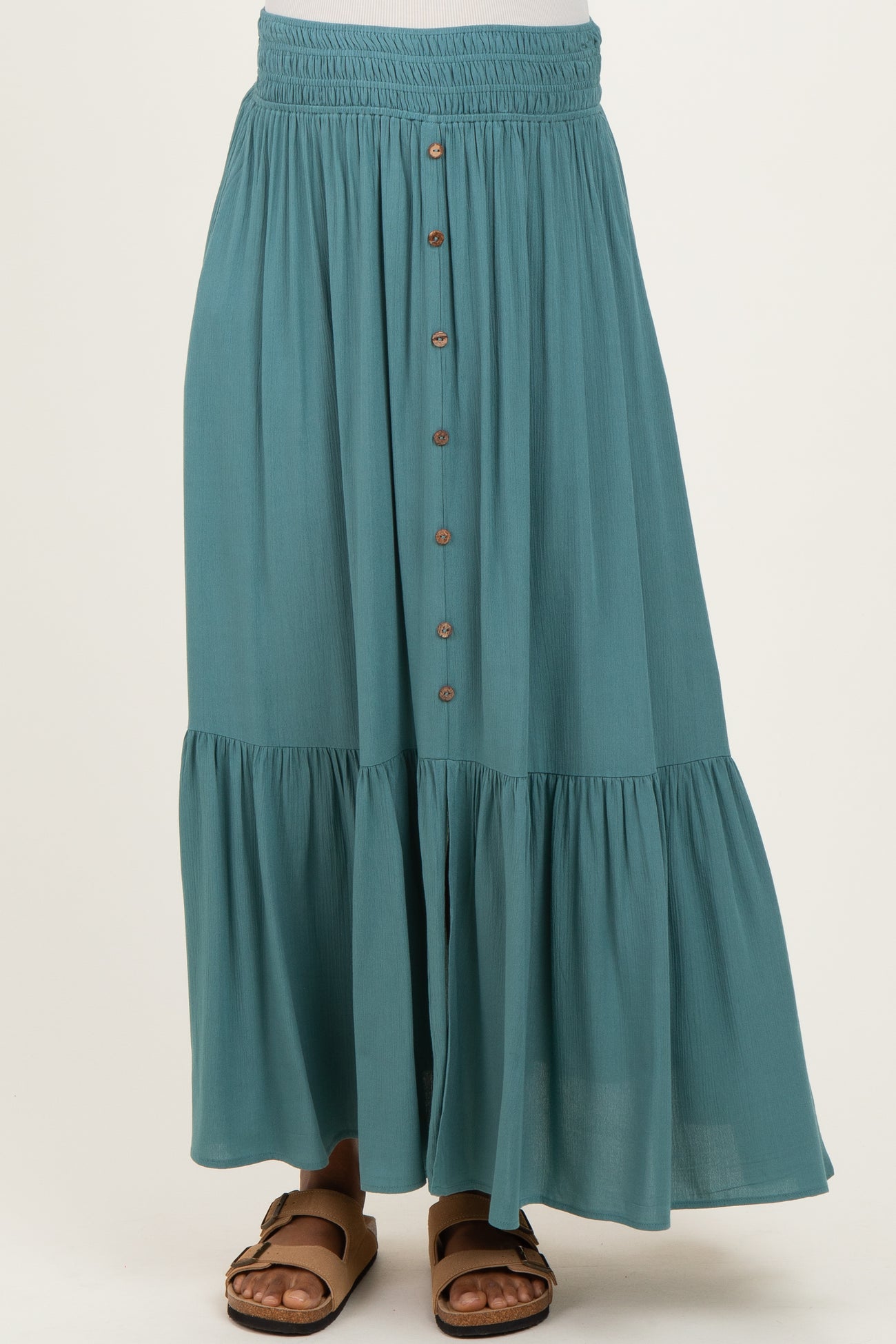 woman wearing a teal maternity skirt with buttons down the front and a tiered hem, styled with sandals