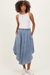 woman wearing a light blue denim maternity skirt with a button front and side pockets, styled with a sleeveless top