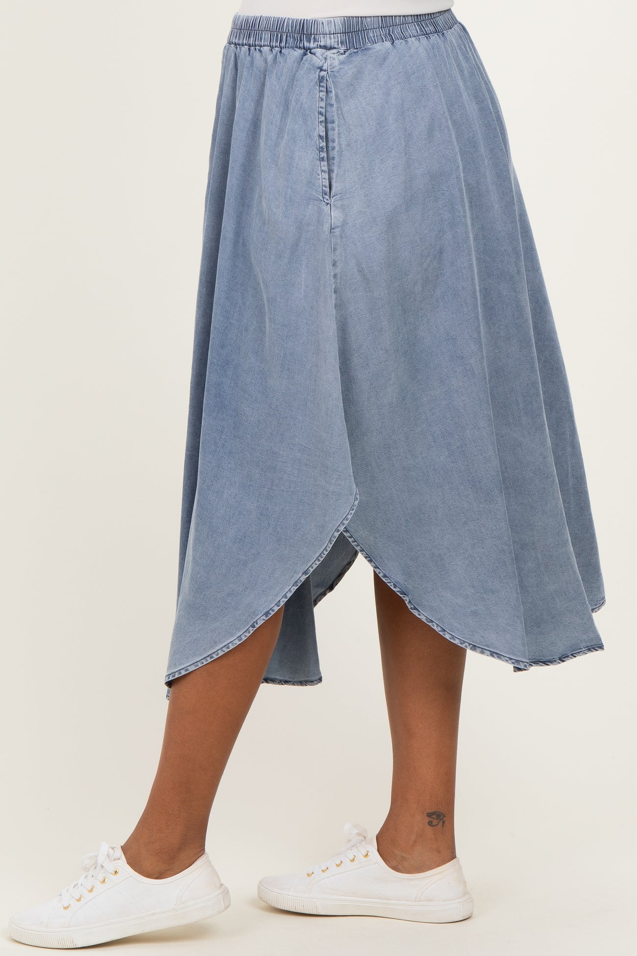 maternity wear light denim wrap skirt with an asymmetrical hem, model wearing white sneakers