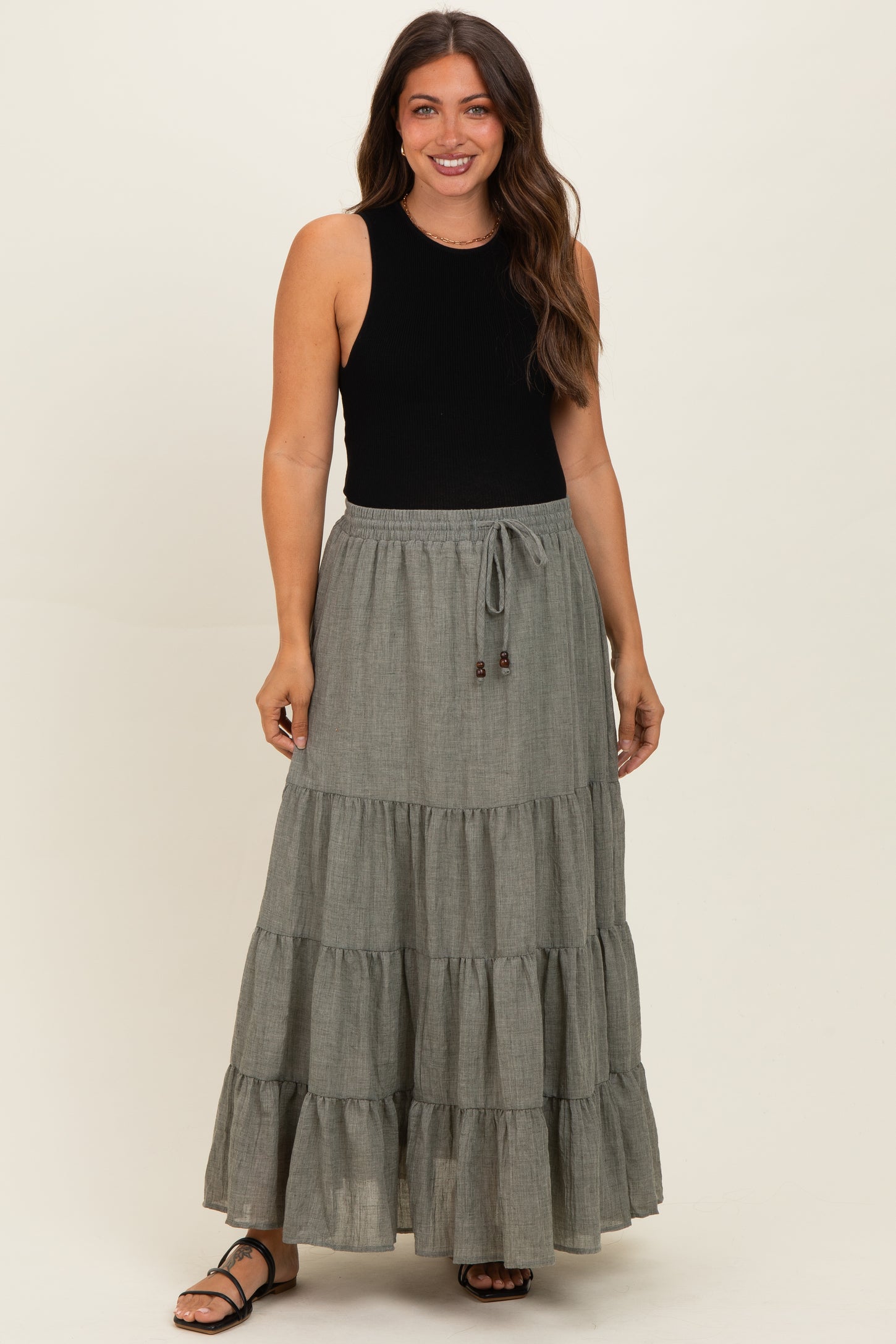 woman wearing a black sleeveless top and a gray tiered maxi maternity skirt with a drawstring waist