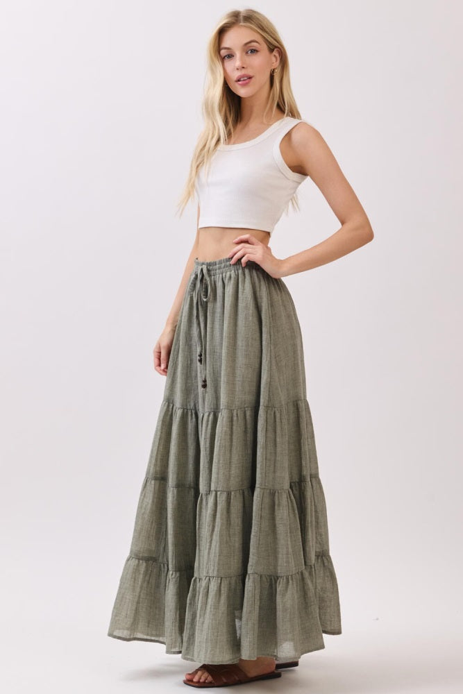 woman wearing a white cropped tank top and a green tiered maxi skirt with a drawstring waistband