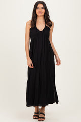 woman wearing a black sleeveless maxi dress with a gathered bodice and side slits