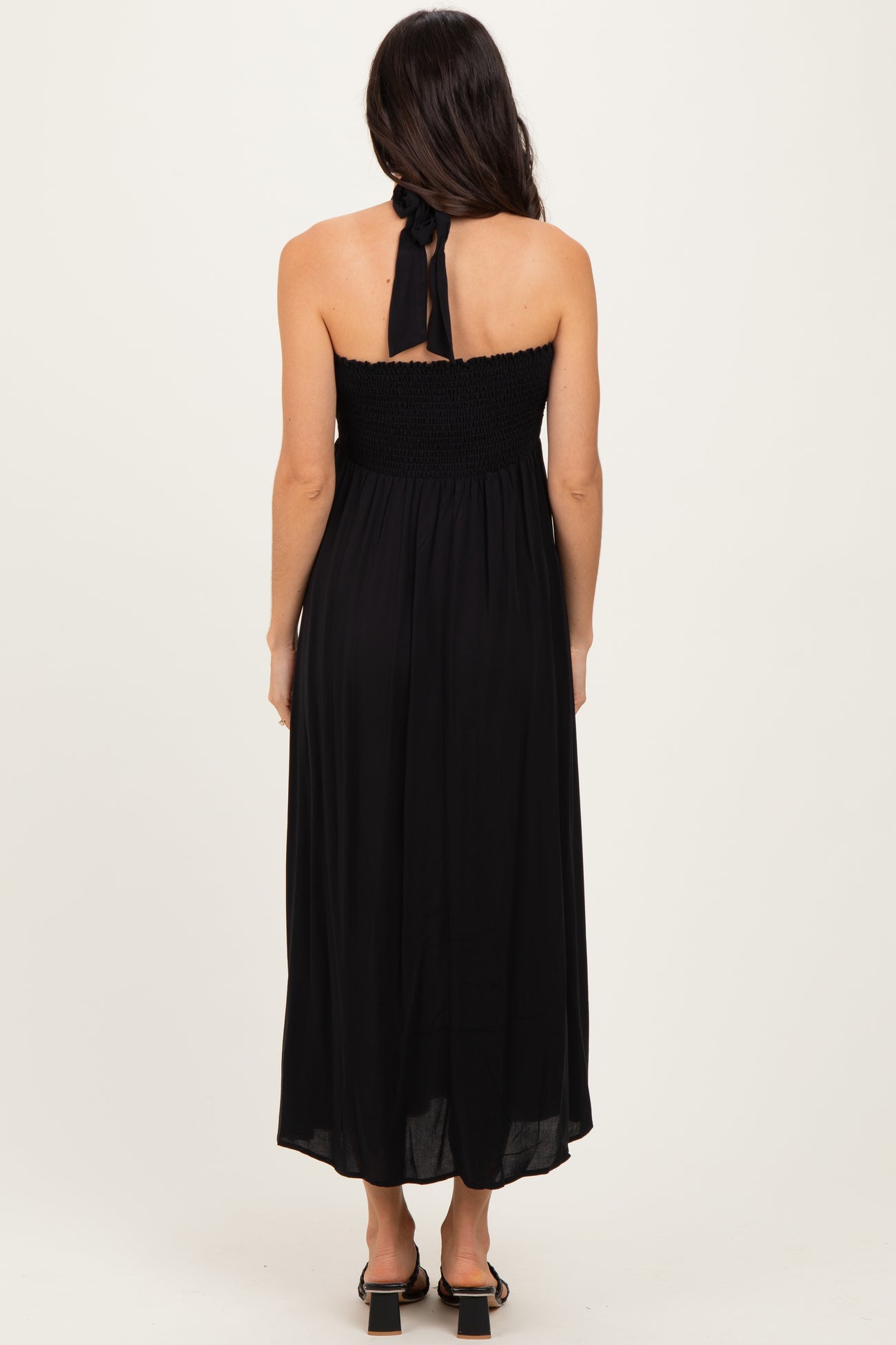 woman wearing a black strapless maxi dress with a smocked bodice and a tie detail at the back