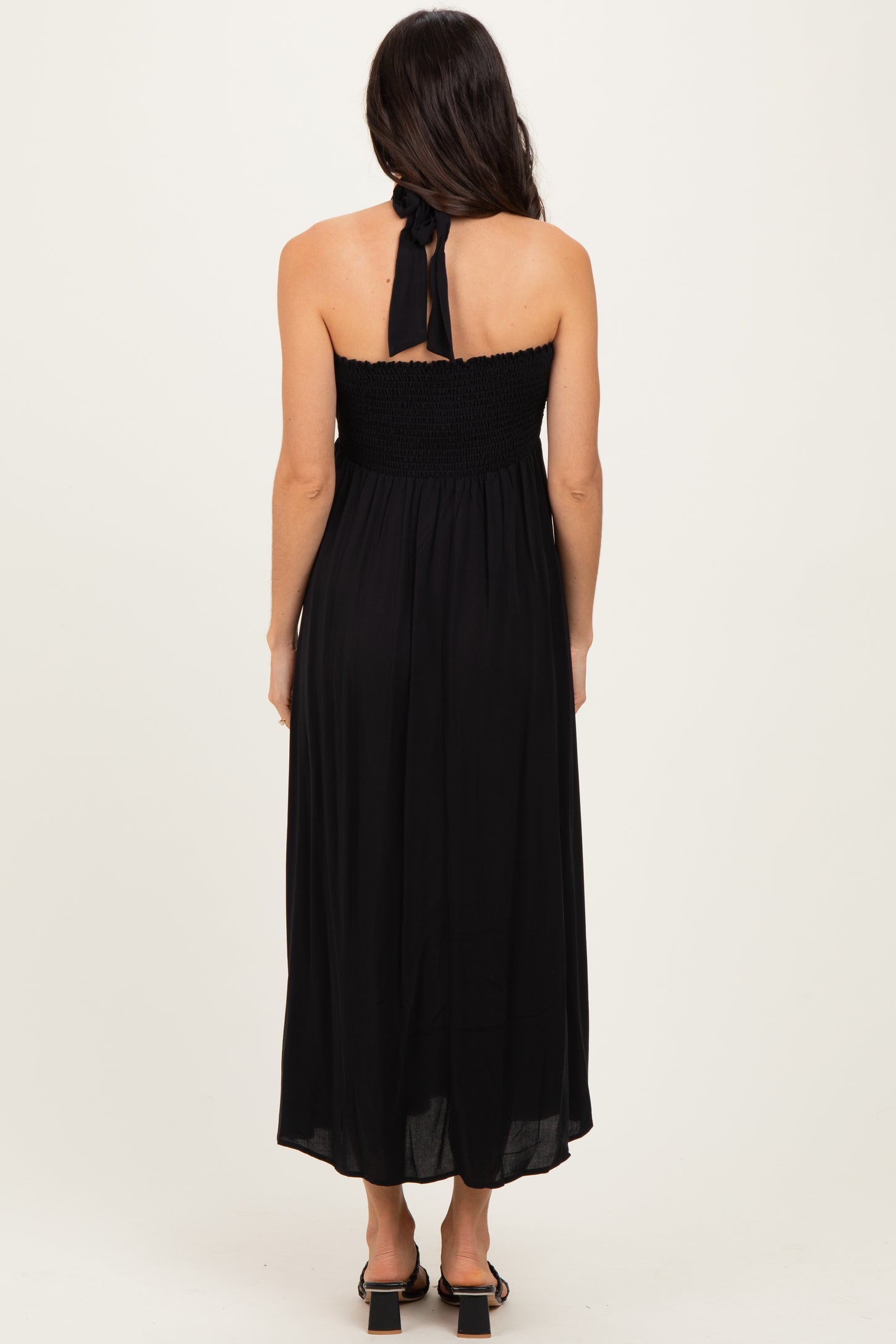 woman wearing a black strapless maxi dress with a smocked bodice and a tie detail at the back