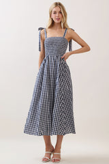 woman wearing a navy and white gingham maxi dress with tie straps and a smocked bodice