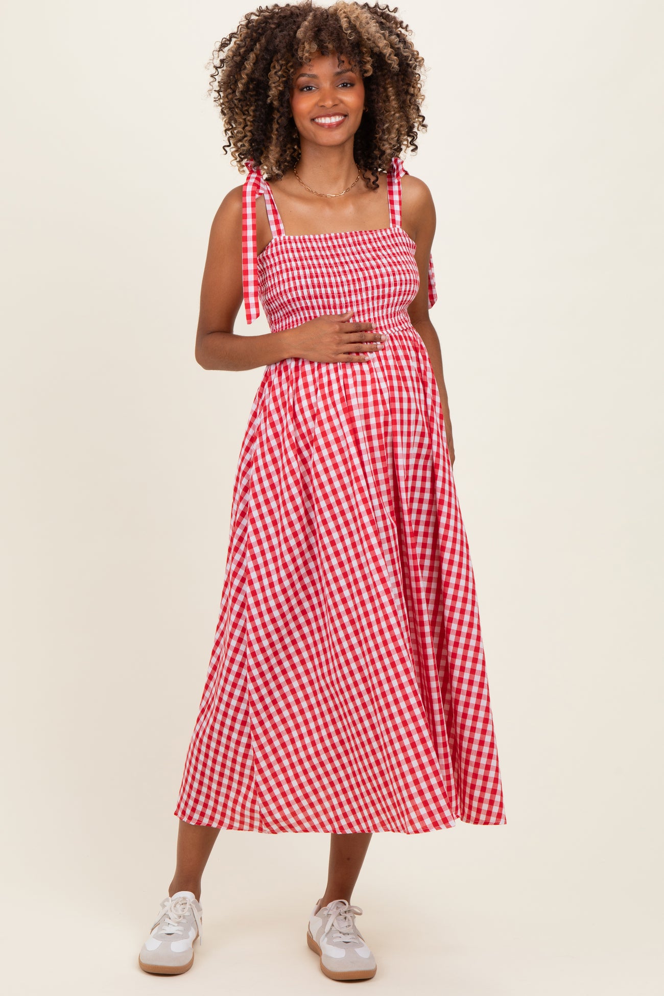 woman wearing a red and white gingham maternity dress with adjustable straps and a visible baby bump