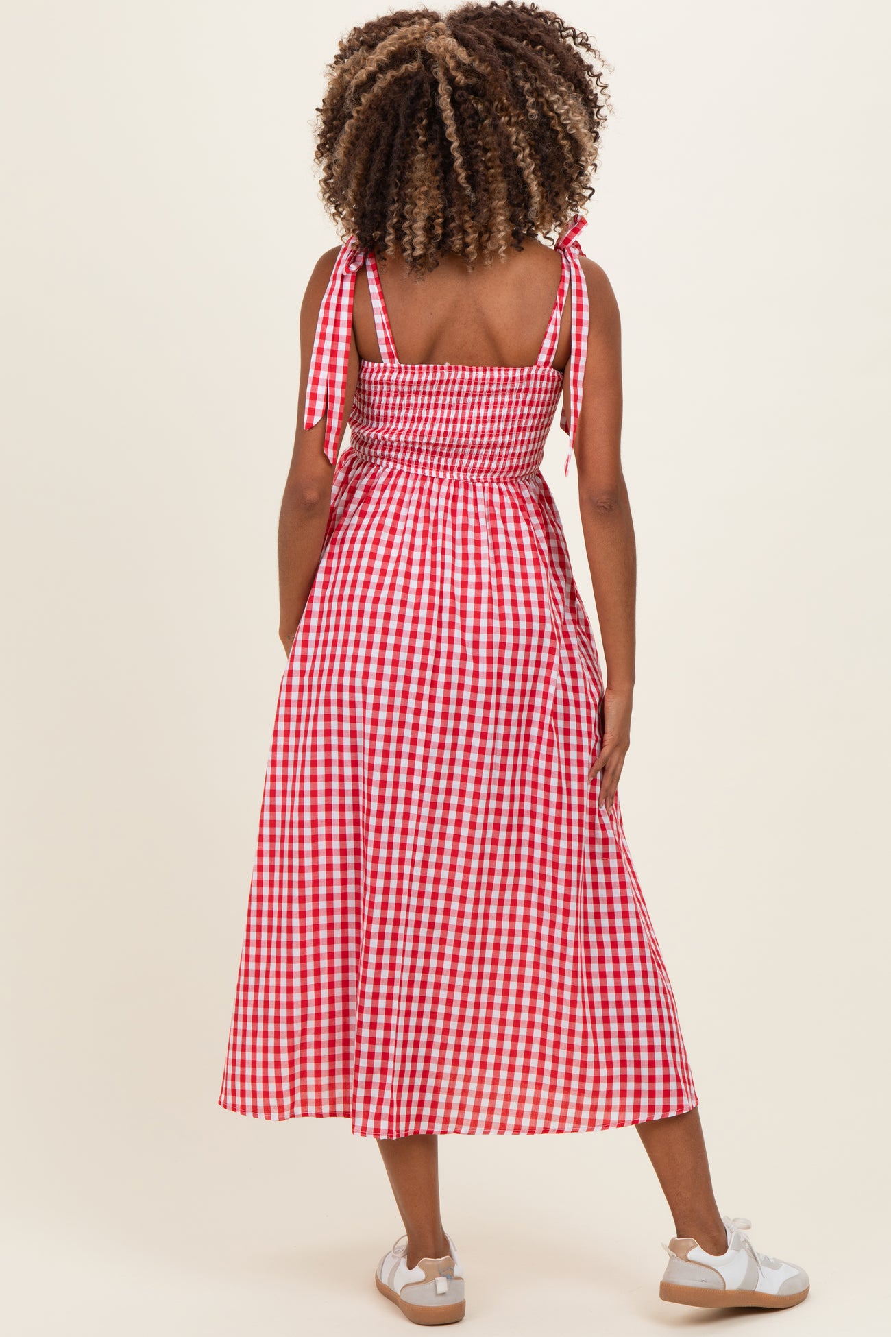 woman wearing a red and white gingham maternity dress with tie shoulders and a smocked back, no baby bump visible