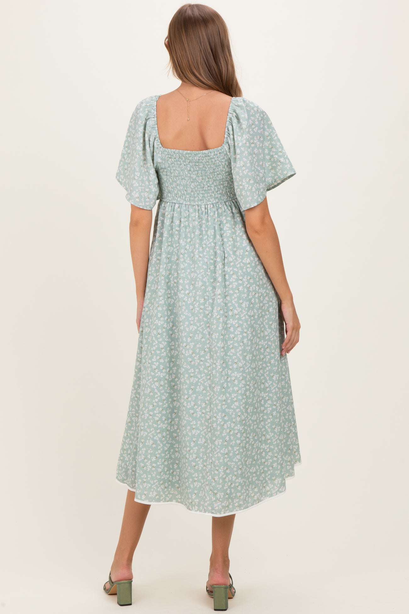 woman wearing a green floral maternity dress with short puff sleeves and a smocked back