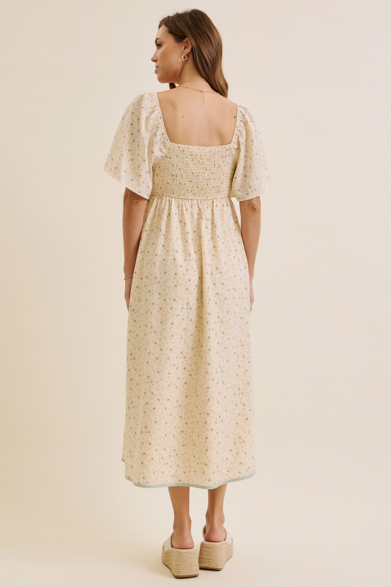 woman wearing a floral midi dress with a square neckline and short puff sleeves, shown from the back