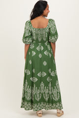 woman wearing a green floral print maternity maxi dress with puff sleeves and a smocked back design