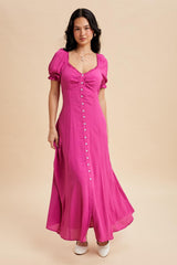 woman wearing a bright pink button-up maxi dress with puff sleeves and a flowy skirt