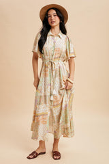 woman wearing a pastel patterned midi dress with short sleeves and a tie belt, accessorized with a hat and sandals