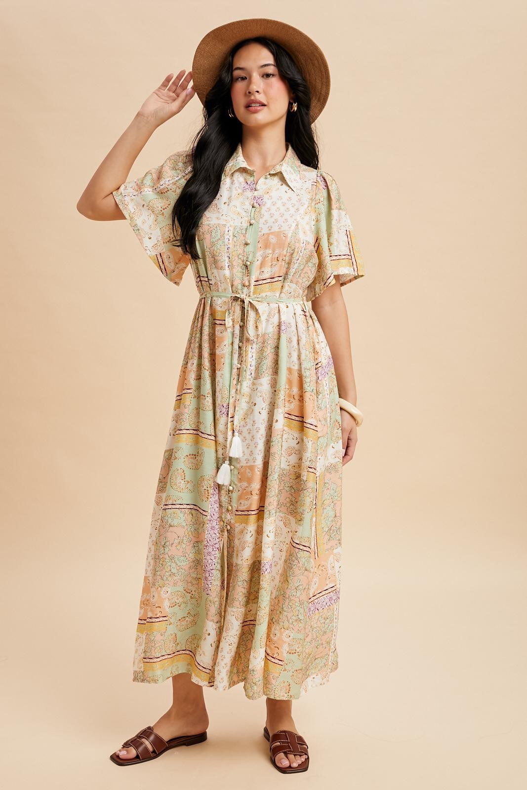 woman wearing a colorful patterned maxi shirt dress with a belt and a wide-brimmed hat