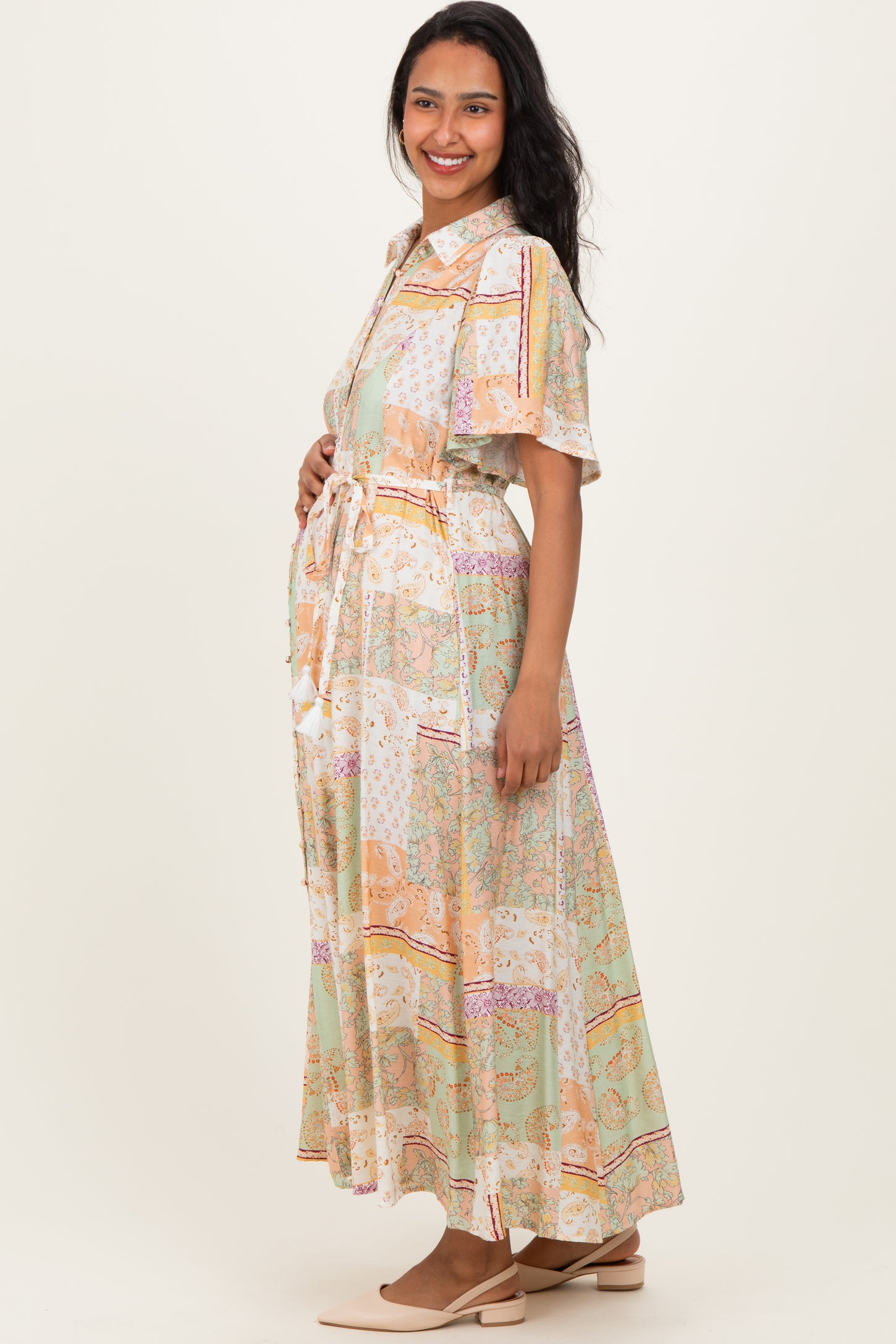 woman wearing a patterned maternity wrap dress and holding her baby bump