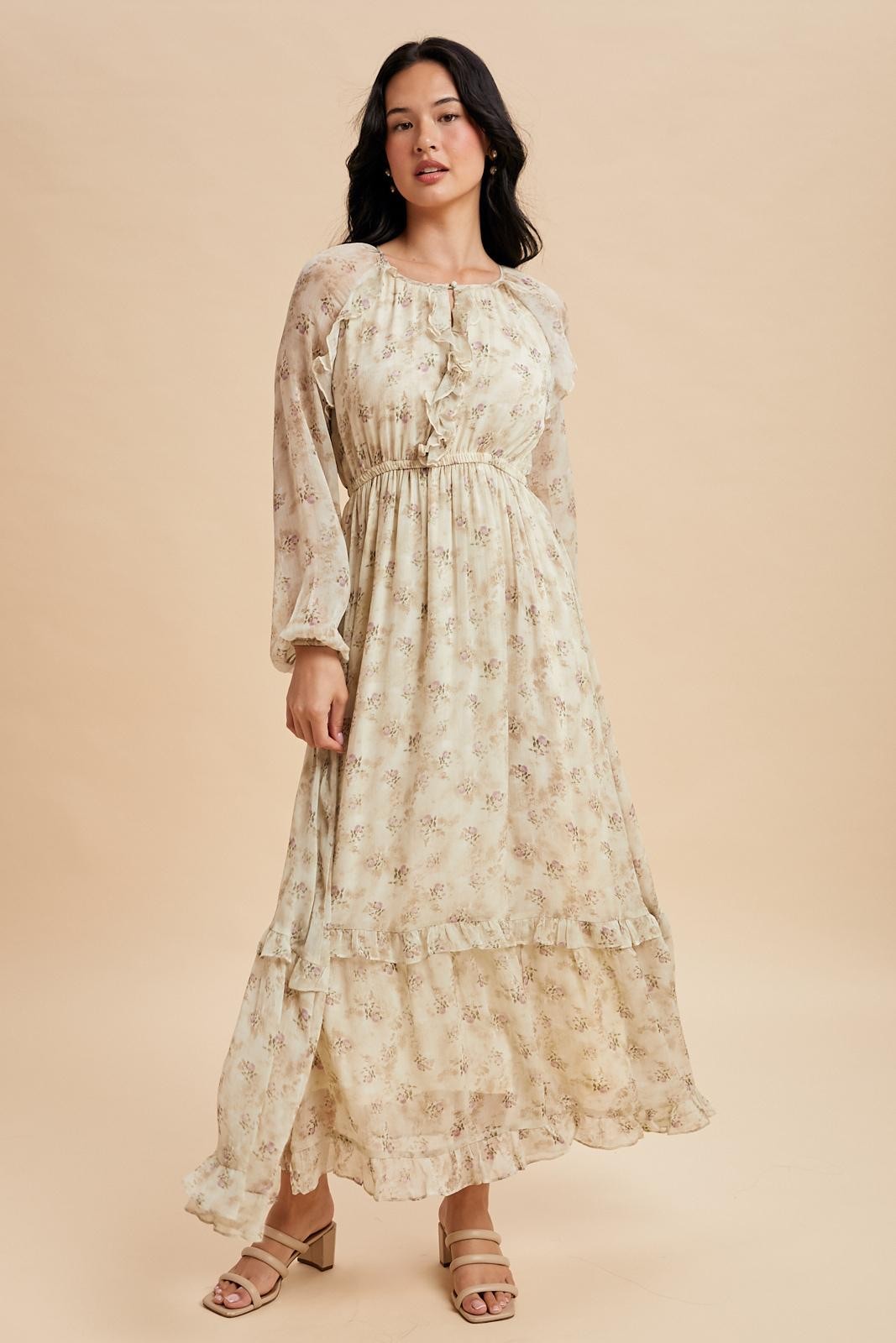 woman wearing a cream floral maxi dress with long sleeves and ruffled hem details