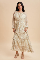 woman wearing a cream floral maxi dress with ruffles and long sleeves, standing on a neutral background