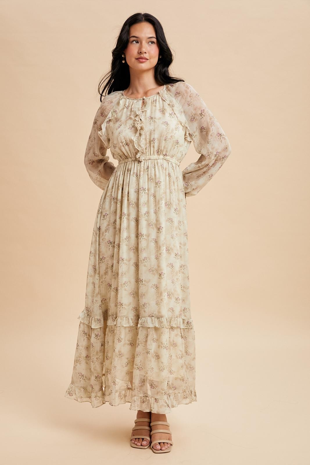 woman wearing a long sleeve beige floral maxi dress with ruffle details and cinched waist