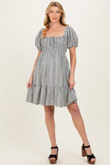 woman wearing a striped maternity dress with puff sleeves and a tiered ruffle hem, featuring a gathered bodice and baby bump visible
