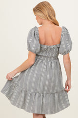 woman wearing a black and white striped maternity dress with puff sleeves and a ruffled hemline, showing her back