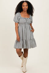 woman wearing a striped puff sleeve dress with a square neckline and ruffled hem, standing with one hand in the pocket
